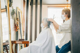 高齢者のヘアカットをする美容師（鏡・横顔）
