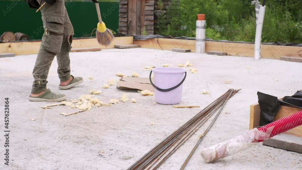 Building Sweeps A builder is sweeping the construction area with a broom. A formwork ...