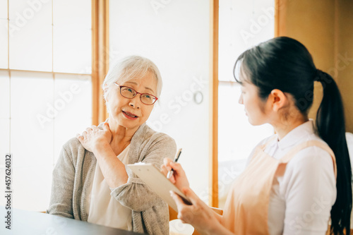 在宅介護を受ける高齢者女性（肩凝り） 