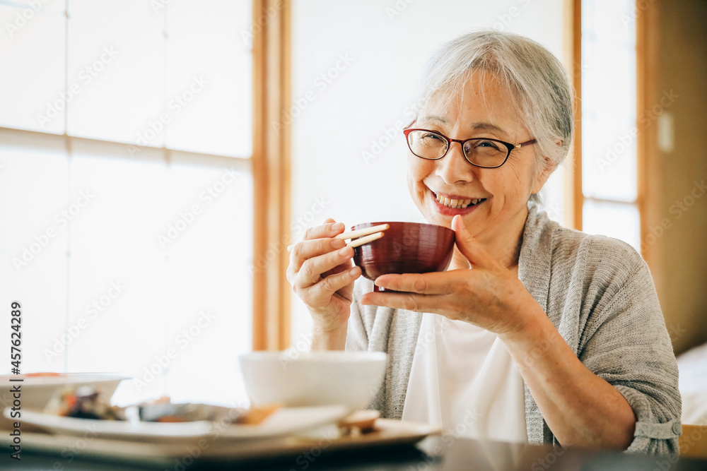 和室で食事を食べる高齢者女性(味噌汁)