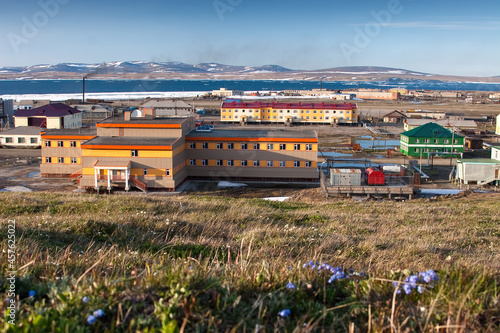 View of a school and residential buildings in a seaside arctic settlement. The Chukotka village of Lavrentiya, located on the shores of the Lawrence Bay in northeastern Russia. Summer in the Arctic. photo