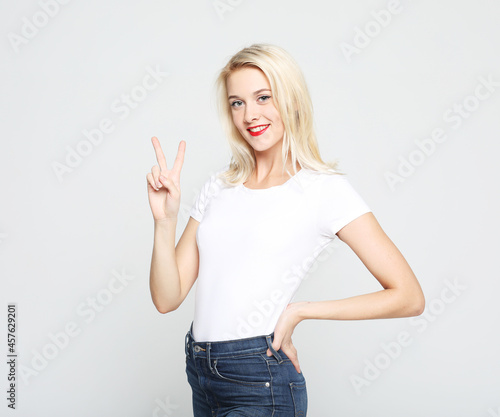 young woman with blond hair wearing white t-shirt show victory sign