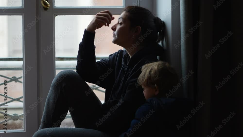 Preoccupied mother sitting by window with toddler. anxious parent Preoccupied mother sitting by window with toddler. anxious parent