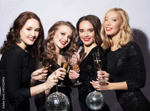 lifestyle, party and people concept - four young women clinking flutes with sparkling wine over white background.
