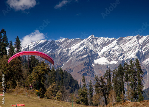 Solang, Himachal Pradesh, India - 2006: Paragider in a valley at Solang near Manali with Himalayan mountain backdrop. Solang Valley is known for its high-altitude summer and winter adventure sports.