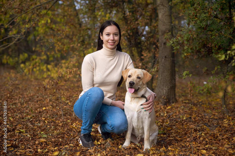 A young woman with a dog in the autumn forest