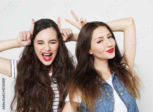 Portrait of two cute playful women showing horns with fingers on head