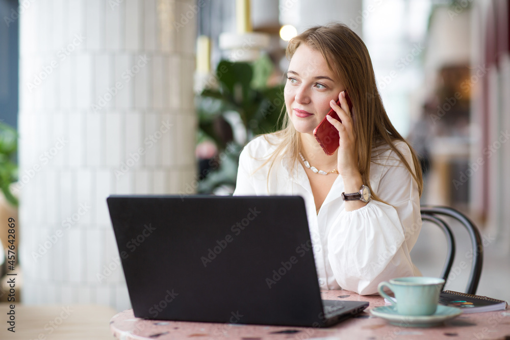 successful business woman sitting in cafe with laptop, working and talking on phone. office workplace with green plants. successful business woman sitting in cafe with laptop, working and talking on phone. office workplace with green plants.