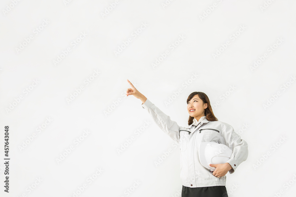 白背景前に立ち 斜め上を指差し見つめろ作業着を着た若い女性 Stock 写真 Adobe Stock