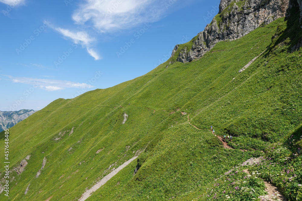 small hiking path over a green steep mountain in the summer of austria small hiking path over a green steep mountain in the summer of austria