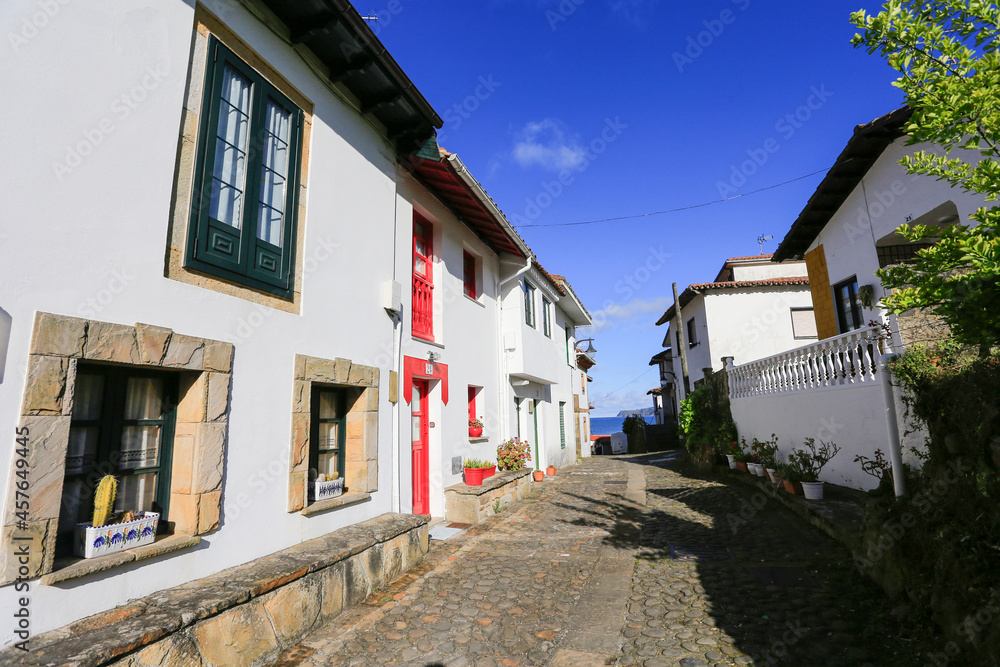 cobbled road between the houses of the fishing port of tazones in asturias, spain. sunny day.