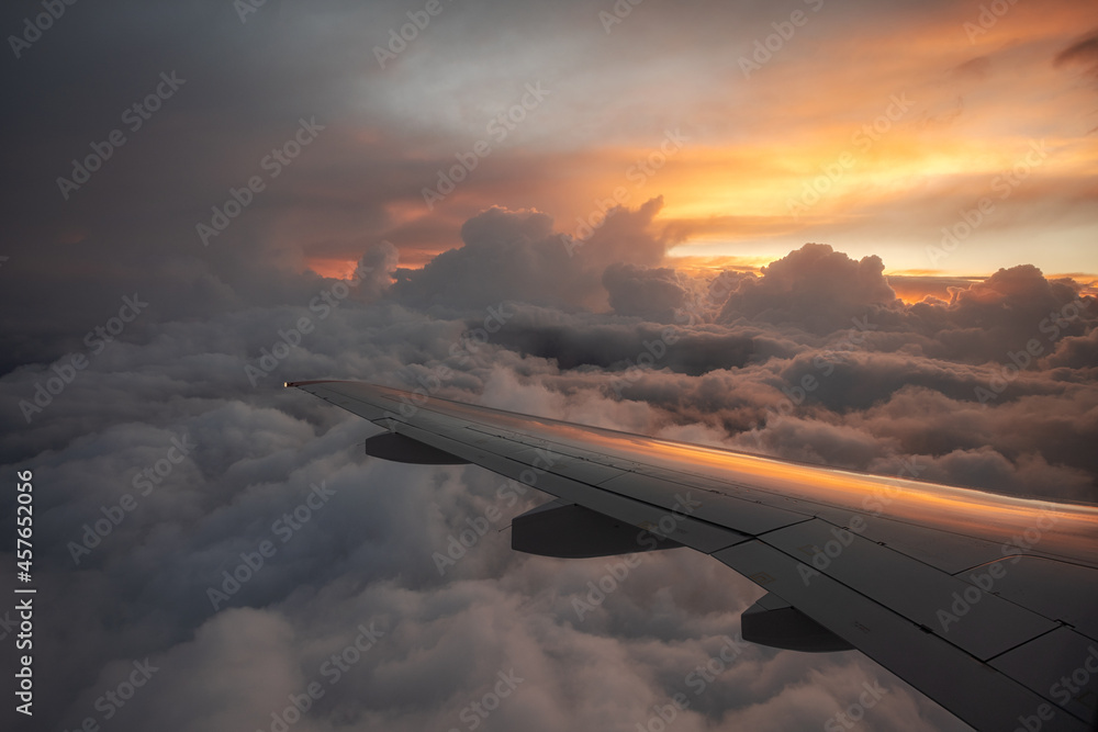 Obraz premium Evening flight over storm clouds. Flight during a storm. View of the beautiful sunset from the plane window.