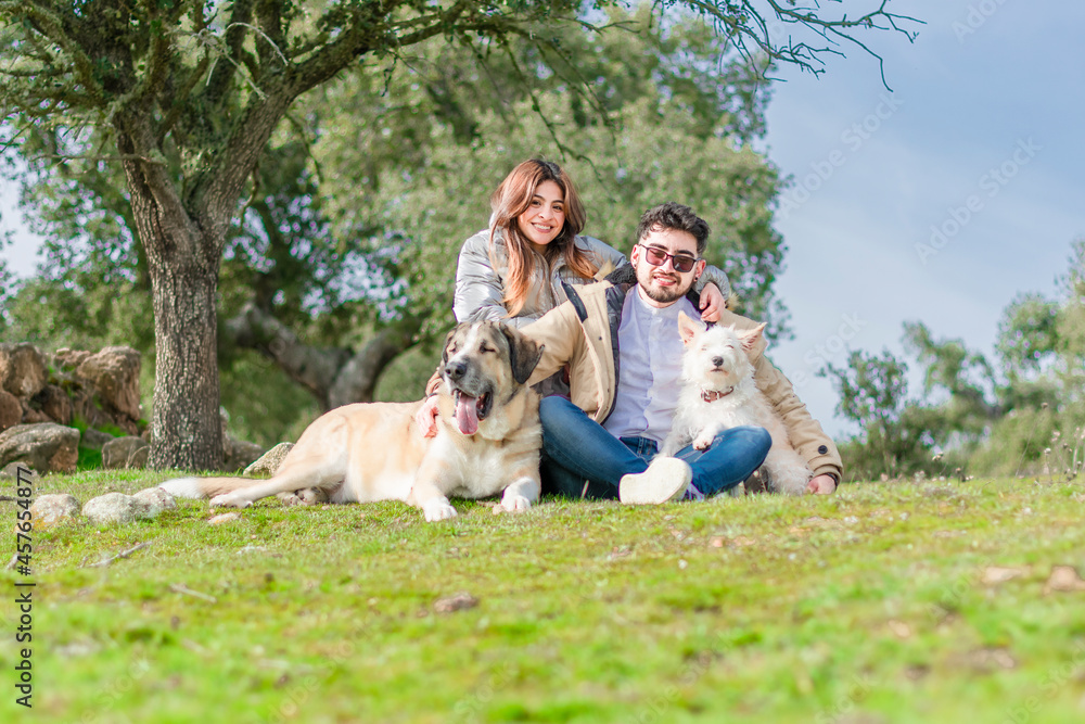 young couple next to an oak tree with two dogs
young couple next to an oak tree with two dogs