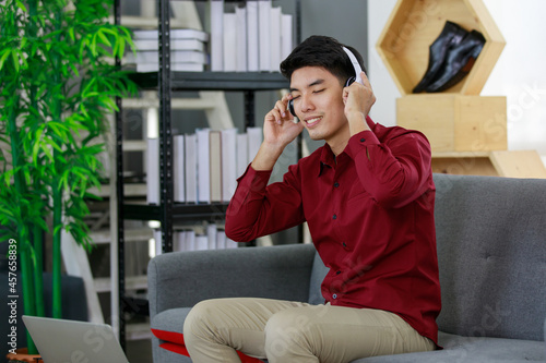 Portrait adult asian man sitting at sofa wearing headphone and close eye to listening feel comfortable and happy