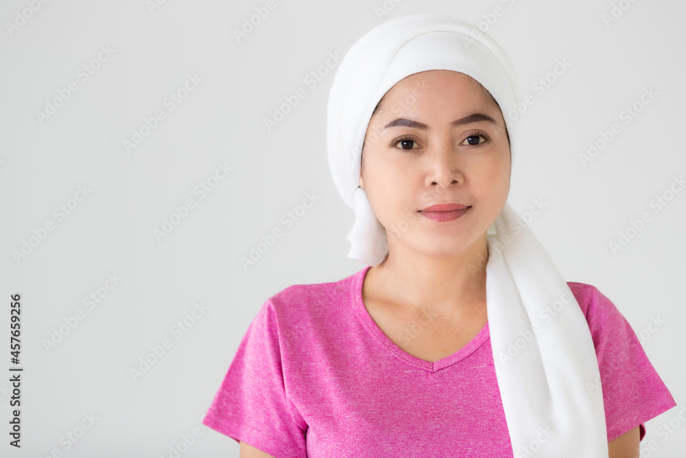Asian woman as hospital patient for breast cancer treatment looks lively and cheerful on pink casual shirt cover head by white clinical scarf to dry hair after bath Asian woman as hospital patient for breast cancer treatment looks lively and cheerful on pink casual shirt cover head by white clinical scarf to dry hair after bath