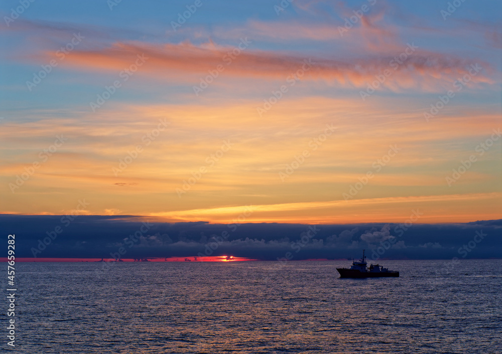 Dawn over the Alvheim Field in the Norwegian North Sea with a Seismic Escort Vessel silhouetted against the rising Sun.