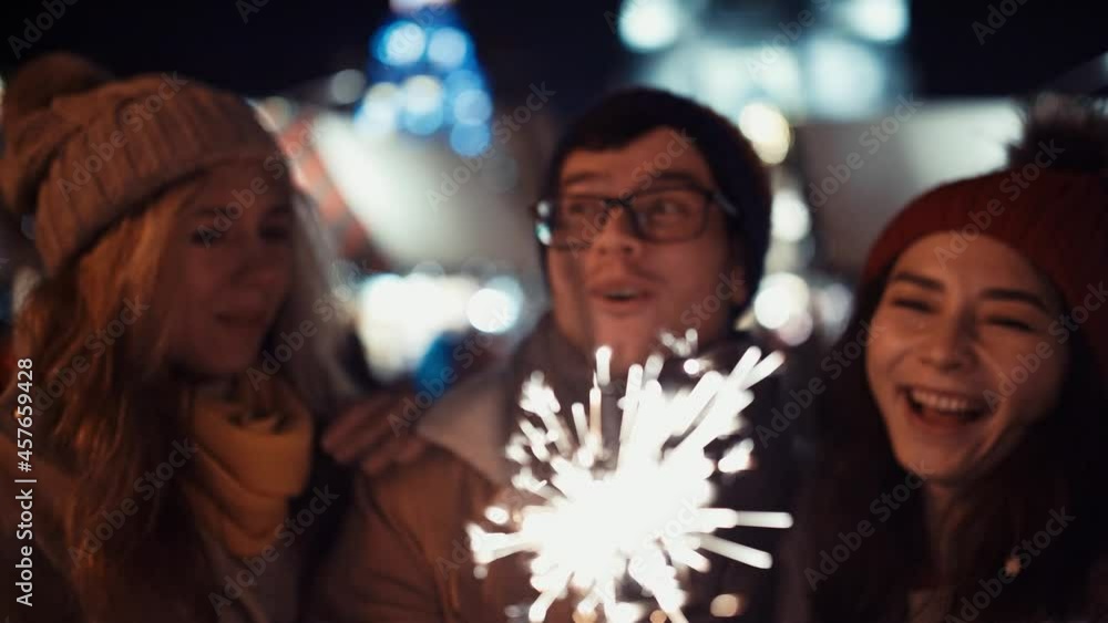 Film Shot. Prores 422. Close Up Portarait of Two girls kiss a happy guy with glasses on new year's eve to the sound of chimes in the middle of the street in the lights of the Christmas market on the Film Shot. Prores 422. Close Up Portarait of Two girls kiss a happy guy with glasses on new year's eve to the sound of chimes in the middle of the street in the lights of the Christmas market on the