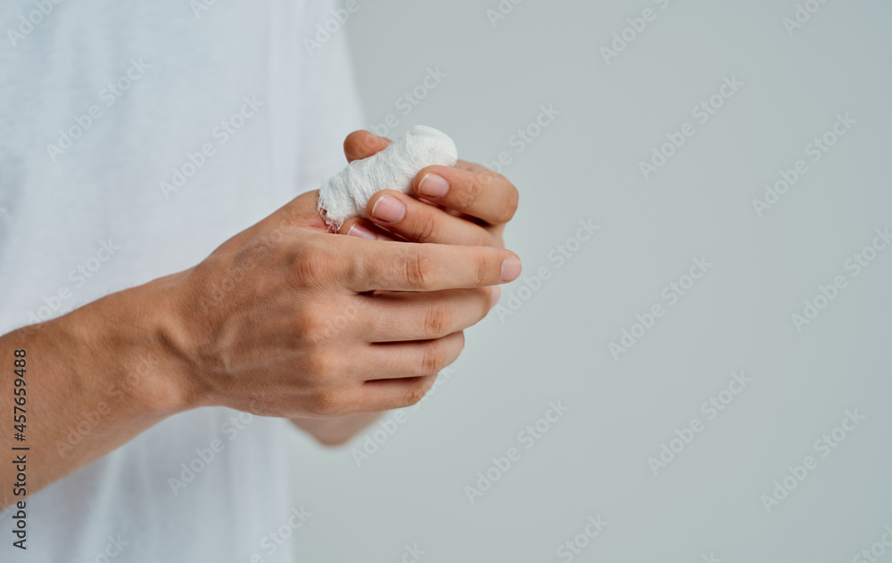 sick man in a white T-shirt with a bandaged hand isolated background sick man in a white T-shirt with a bandaged hand isolated background