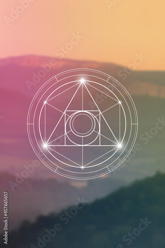 Philosopher stone sacred geometry spiritual new age futuristic illustration with transmutation interlocking circles, triangles and glowing particles in front of blurred natural background.