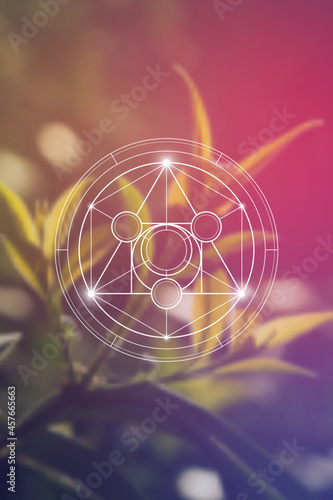 Philosopher stone sacred geometry spiritual new age futuristic illustration with transmutation interlocking circles, triangles and glowing particles in front of blurred natural background.