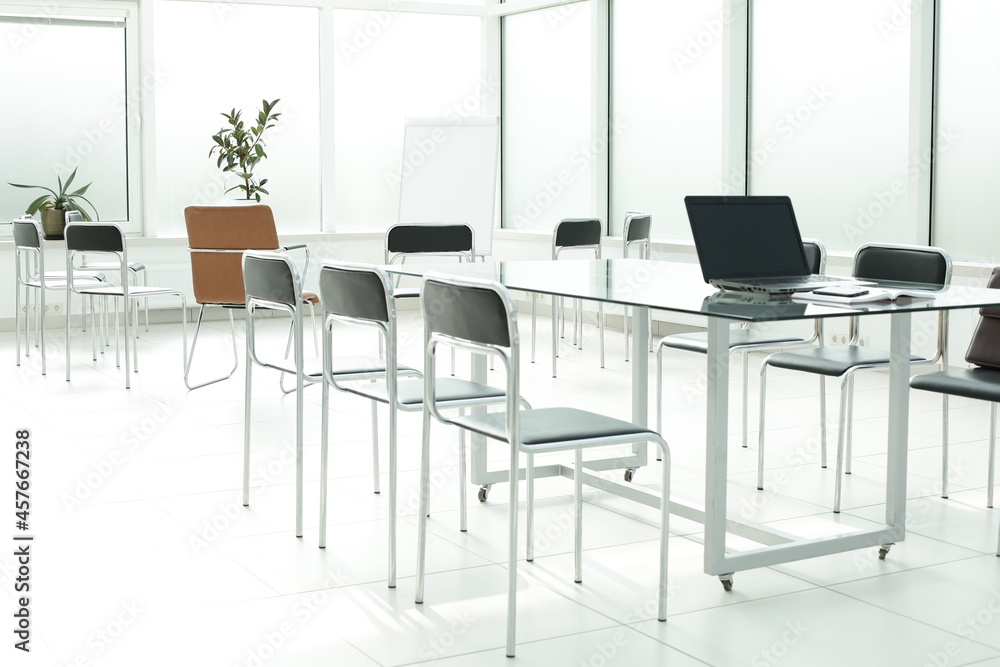 Flipchart laptop chairs and glass table in a bright office space Flipchart laptop chairs and glass table in a bright office space