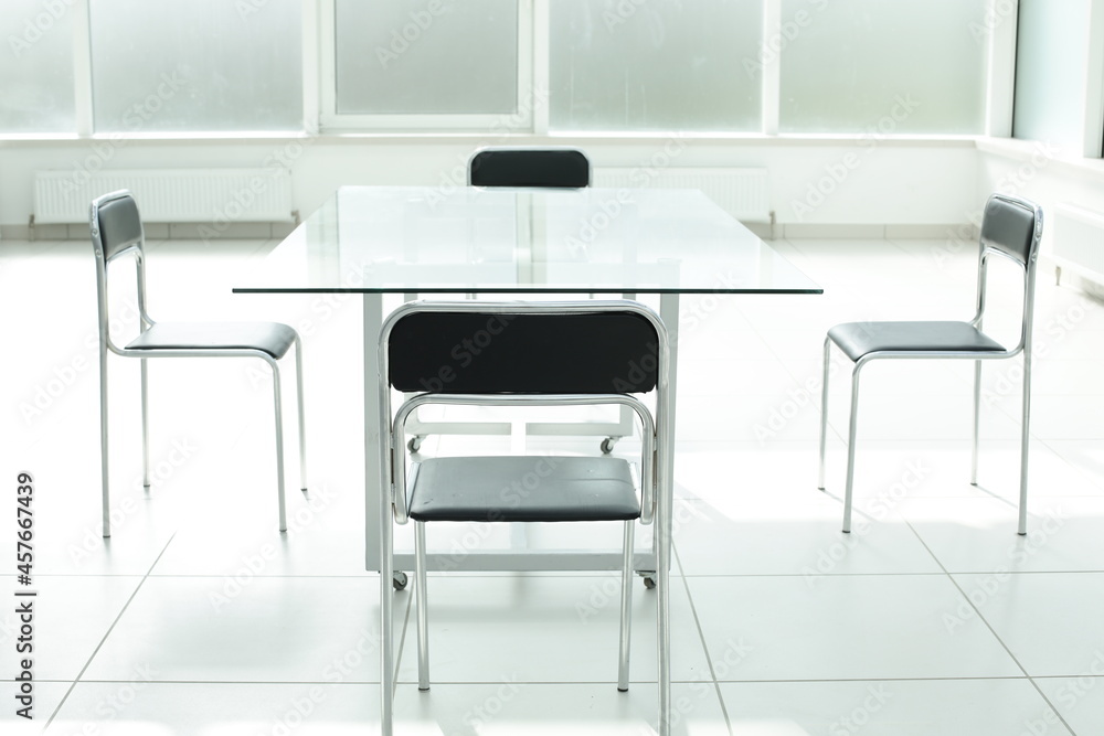Fototapeta premium Glass table and chairs in a bright office space