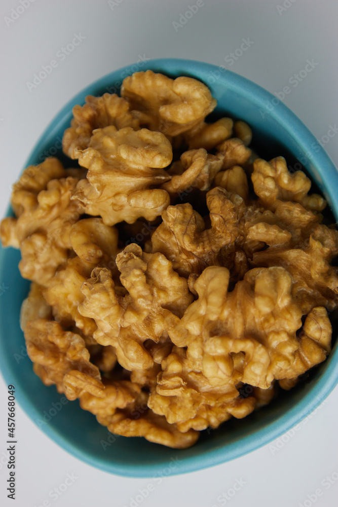 Walnuts in Blue Bowl White Background Vertical Close Up Bird's Eye View