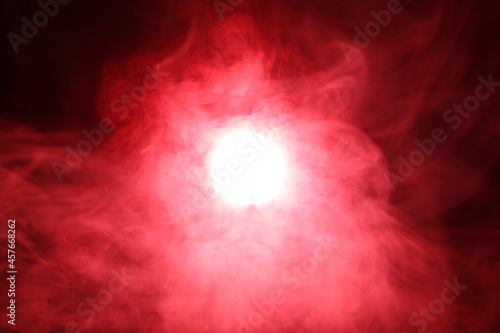 Artificial magic smoke in red light on black background