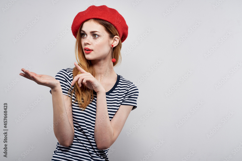 pretty woman in a striped t-shirt red lips gesture with his hands light background pretty woman in a striped t-shirt red lips gesture with his hands light background