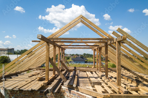 Aerial view of unfinished house with wooden roof frame structure under construction.