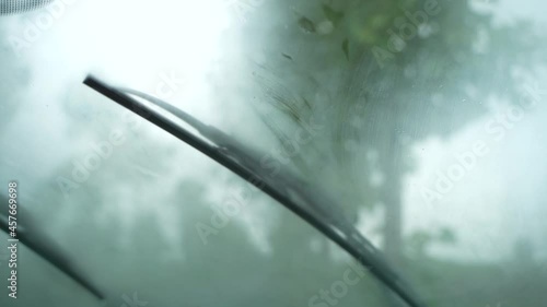 The view from the front window of the car with working windshield wipers during heavy rain while moving.