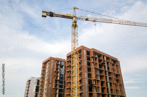 High-rise residential apartment buildings and tower crane under development on construction site. Real estate development. © bilanol