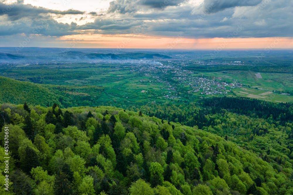 Aerial view of dark mountain hills covered with green mixed pine and lush forest in evening.