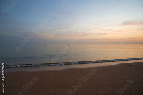Calm sea shore with crushing waves on sandy beach at sunrise.