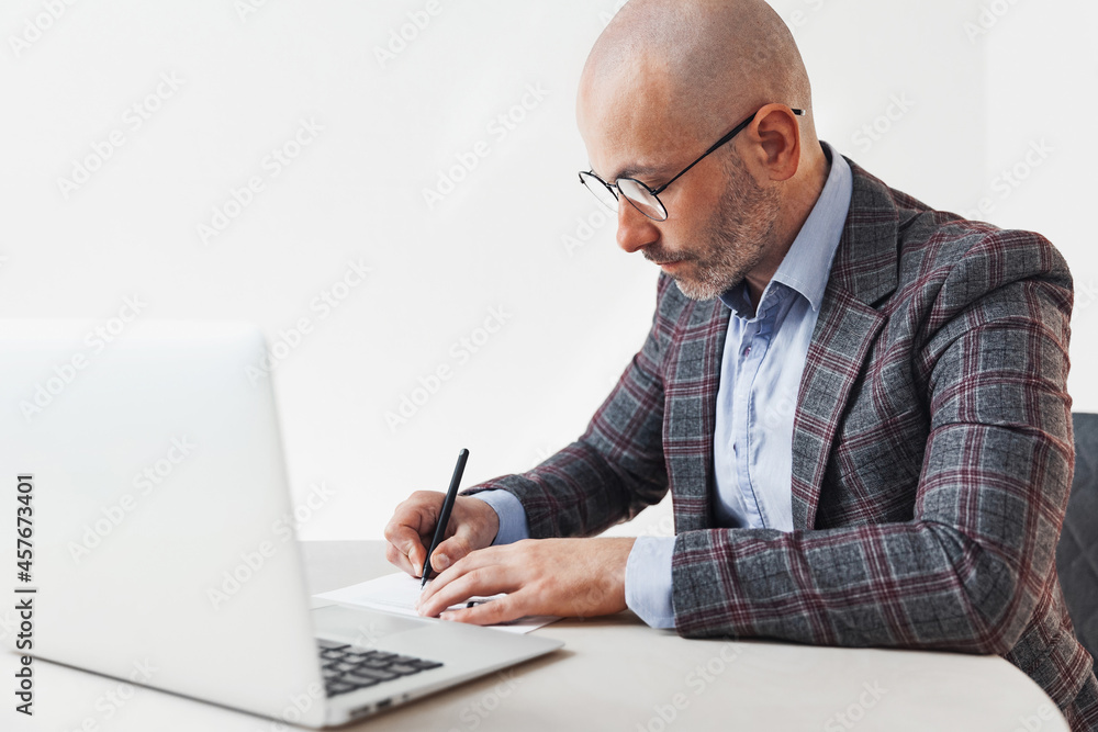 Adult man in a suit writing in a document at the workplace Adult man in a suit writing in a document at the workplace
