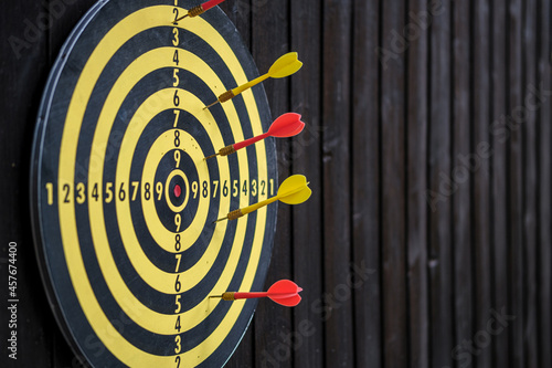 Dart board with yellow and red darts. Close-up. Side view. Copy space. Selective focus