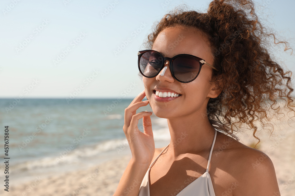 Beautiful African American woman with sun protection cream on nose at beach Beautiful African American woman with sun protection cream on nose at beach