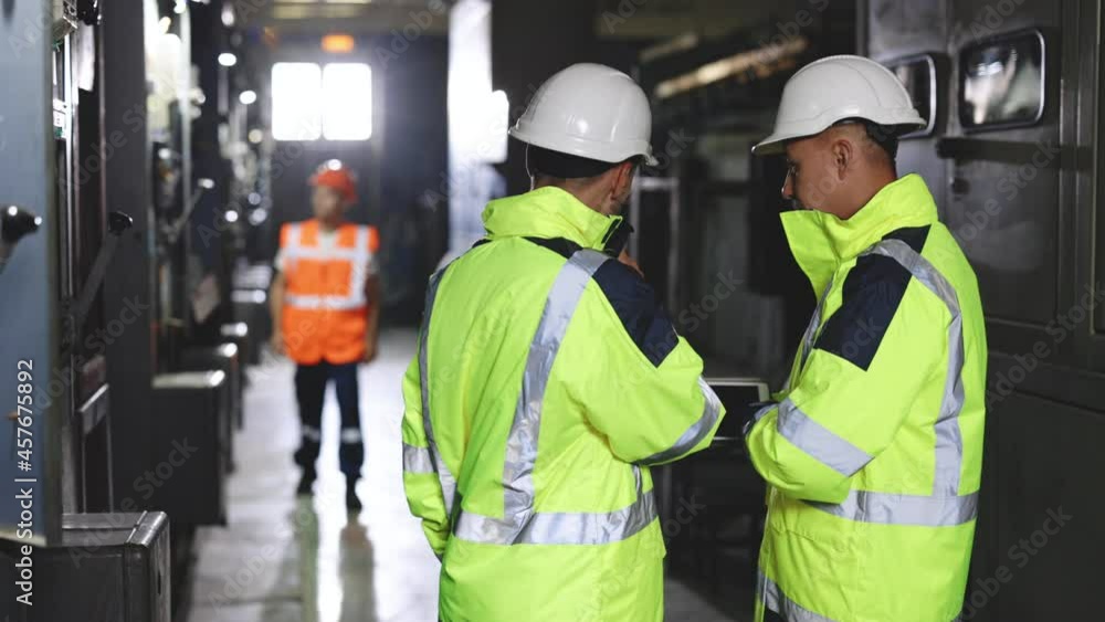 Two Heavy Industry Engineers Stand in Pipe Manufacturing Factory, Use Digital Tablet Computer, Have Discussion. Facility for Construction of Oil, Gas and Fuel Pipeline Transportation Products. Two Heavy Industry Engineers Stand in Pipe Manufacturing Factory, Use Digital Tablet Computer, Have Discussion. Facility for Construction of Oil, Gas and Fuel Pipeline Transportation Products.