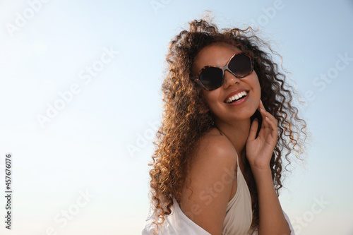 Beautiful African American woman with sunglasses against blue sky. Sun protection care © New Africa