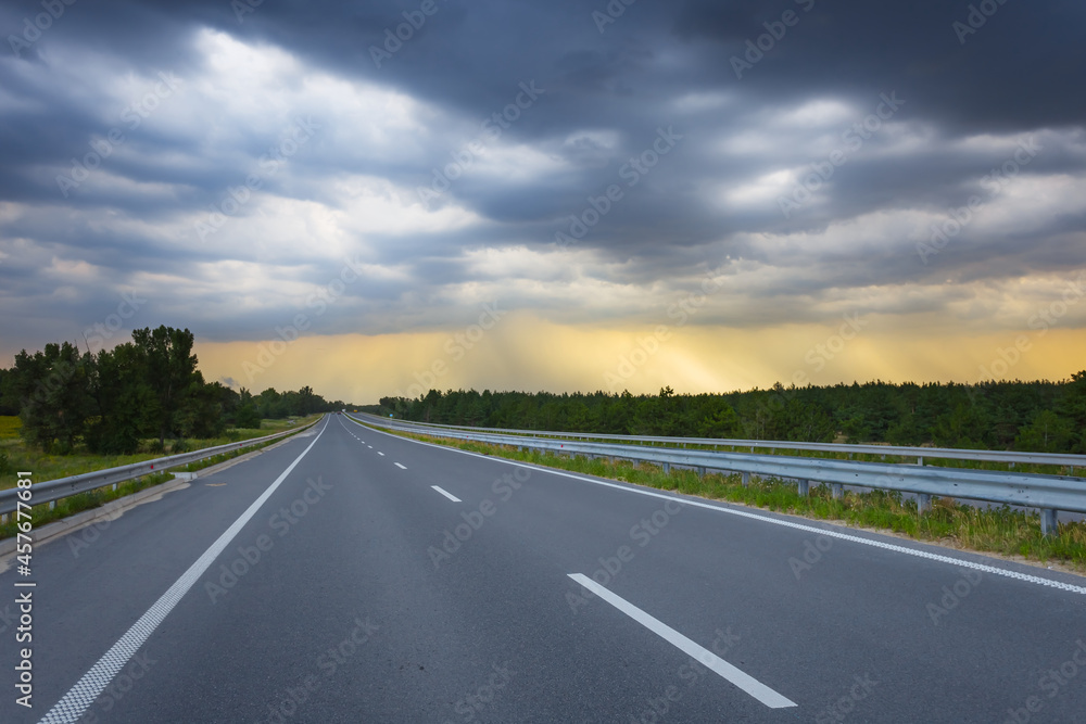 asphalt road leaving far under dense cloudy sky, transportation scene