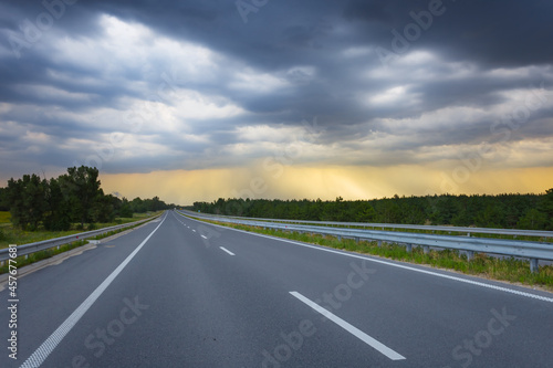 asphalt road leaving far under dense cloudy sky, transportation scene © Yuriy Kulik