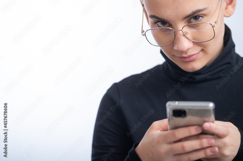 Young caucasian woman with short hair uses a smartphone on a white background. Young caucasian woman with short hair uses a smartphone on a white background.