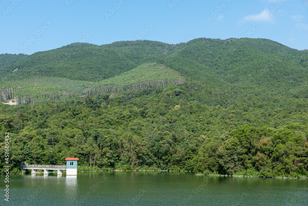 The scenery beside the reservoir is blue sky, white clouds, green mountains and clear water