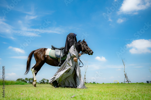 Portrait of a Muslim woman with a horse at the meadow