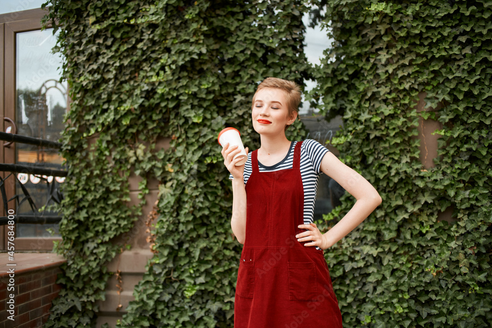 Fototapeta premium short haired woman outdoors a cup of drink lifestyle shrubs