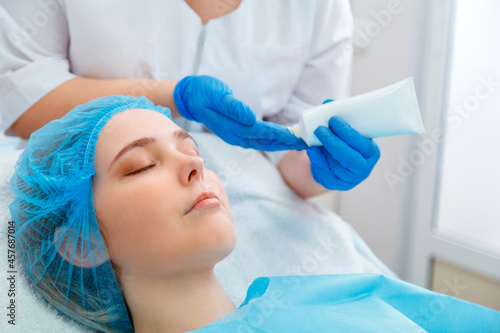 Beautician do beauty procedure for woman client. Beautician doctor dermatologist apply moisturizing cream or cream mask on female face. Cosmetic spa procedure in beauty salo or clinic