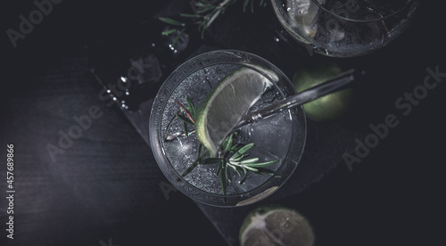 banner of classic gin and tonic cocktail with rosemary sprigs in tall glasses on a table with bar accessories