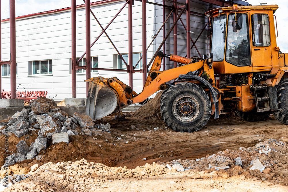 A front-end loader at a construction site removes debris from reinforced concrete. Collection and removal of detached building materials. A front-end loader at a construction site removes debris from reinforced concrete. Collection and removal of detached building materials.