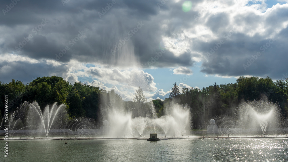 Water from the fountain. Top of high water stream of fountain behind cloudy sky. Fountain in river against dramatic sky. Cityscape view.