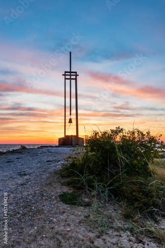 Vertical photo of dedicatory for children lost in shipwreck of ferryboat Estonia on Tahkuna peninsula, Hiiumaa, Estonia. Low angle photo of bush and memorial with bell during dawn.  photo